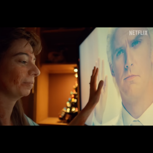 Screenshot still from Cabinet of Curiosities: “The Outside” (2022, Netflix). A woman with blotchy, damaged skin reaches out to touch a glowing television screen showing a man in a white suit mirroring her gesture. Used for commentary in a Hallowe’en body horror blog.